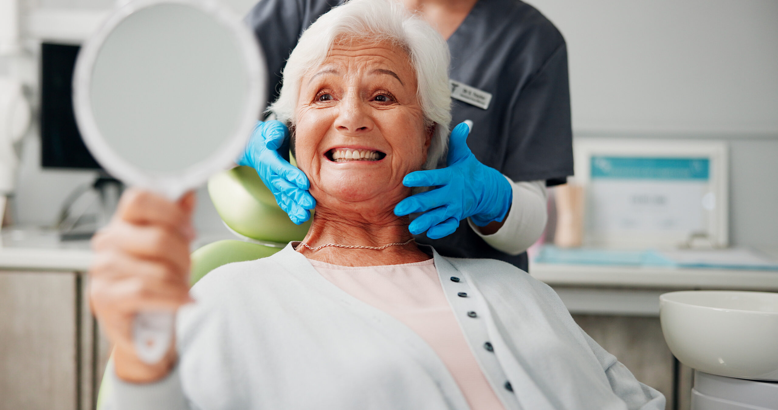 Dentist, senior woman and happy with mirror for tooth cleaning results, dental implant or filling. Retirement, healthcare or doctor with elderly patient in clinic for dentures or root canal treatment.