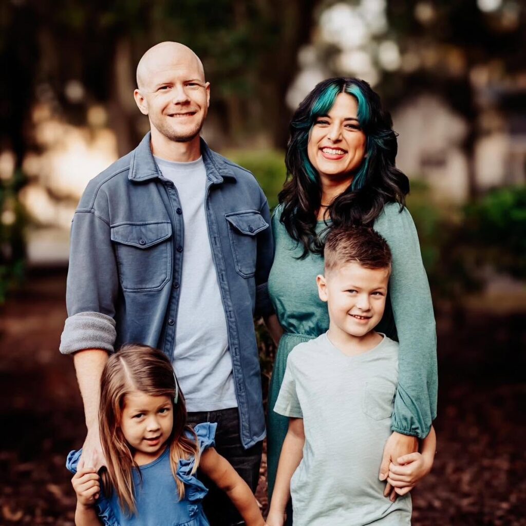 Dr. Grason Hadfield smiling outdoors with his wife and two young children